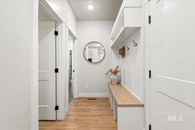 mudroom featuring light wood-style flooring, visible vents, and baseboards