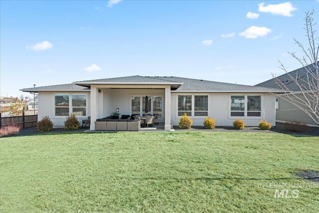 rear view of house featuring stucco siding, fence, an outdoor living space, and a yard