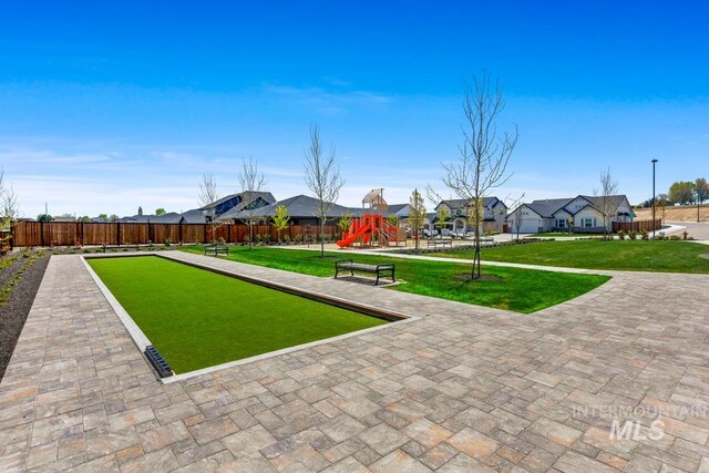 view of property's community featuring a residential view, fence, playground community, and a yard