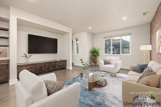 living room featuring recessed lighting, wood finished floors, baseboards, and a textured ceiling