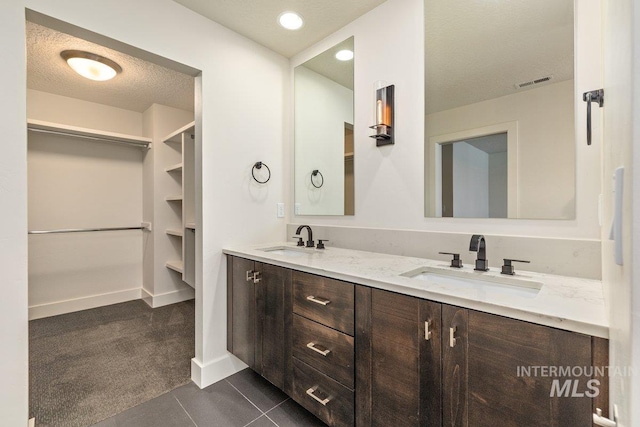 full bathroom featuring a sink, visible vents, double vanity, and a spacious closet