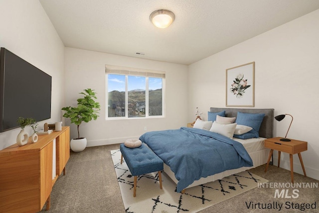 carpeted bedroom featuring visible vents, baseboards, and a textured ceiling