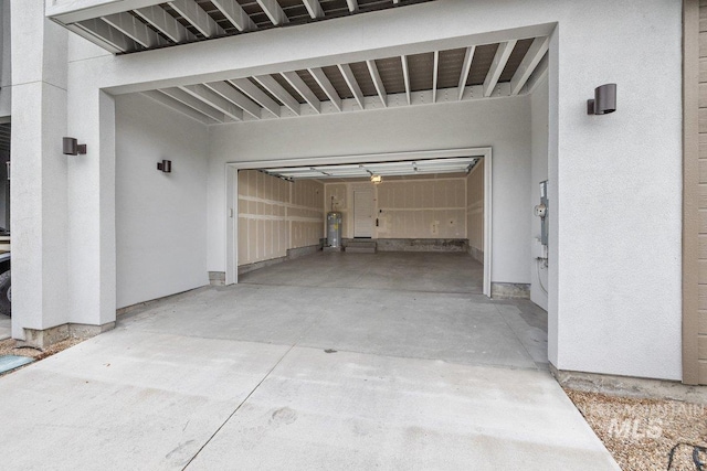 garage featuring concrete driveway and water heater