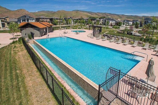 community pool with a patio area, a mountain view, and fence