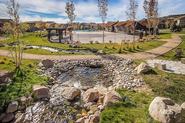 view of community featuring a swimming pool, a residential view, and fence