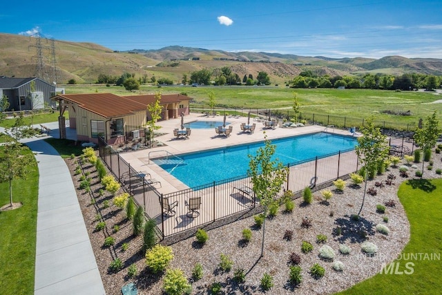 pool featuring a patio, fence, and a mountain view