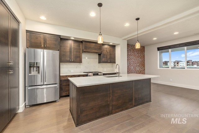 kitchen with wood finished floors, stainless steel fridge with ice dispenser, a sink, light countertops, and dark brown cabinets