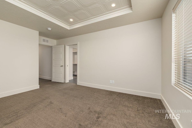 unfurnished bedroom with a raised ceiling, an ornate ceiling, recessed lighting, dark colored carpet, and baseboards