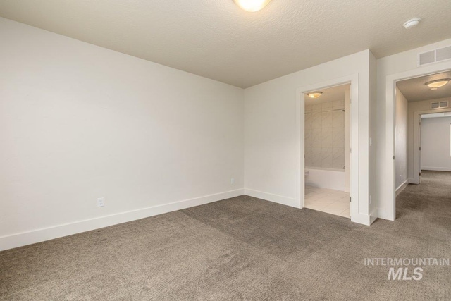 carpeted empty room with visible vents, baseboards, and a textured ceiling