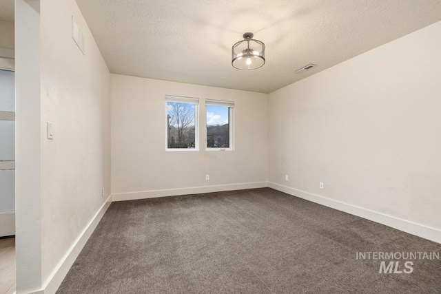 unfurnished room featuring dark colored carpet, visible vents, baseboards, and a textured ceiling