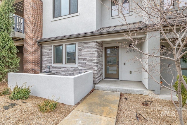 property entrance featuring a standing seam roof, stucco siding, stone siding, and metal roof