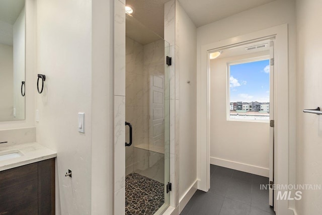 bathroom featuring vanity, visible vents, baseboards, a shower stall, and tile patterned floors