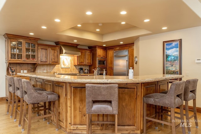 221 Picabo Street #D, Interest 1-H, Ketchum, ID 83340 - kitchen featuring built in appliances, brown cabinetry, wall chimney range hood, light wood-type flooring, and recessed lighting