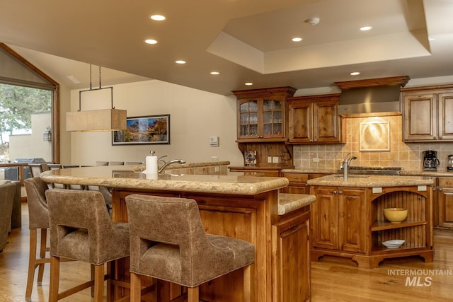 221 Picabo Street #D, Interest 1-H, Ketchum, ID 83340 - kitchen featuring an island with sink, wall chimney exhaust hood, brown cabinets, open shelves, and recessed lighting
