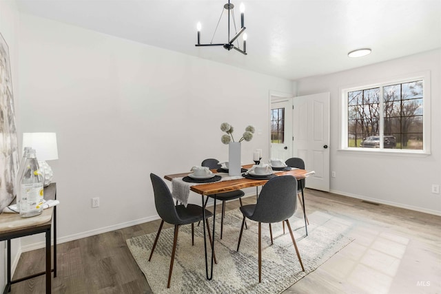 dining space with a chandelier, wood finished floors, and baseboards
