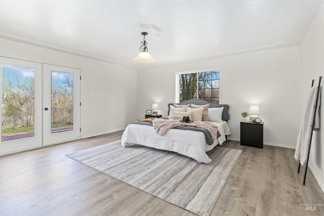 bedroom with access to exterior, light wood-type flooring, and baseboards