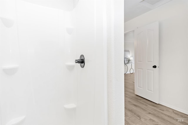 full bath featuring a shower, wood finished floors, and baseboards