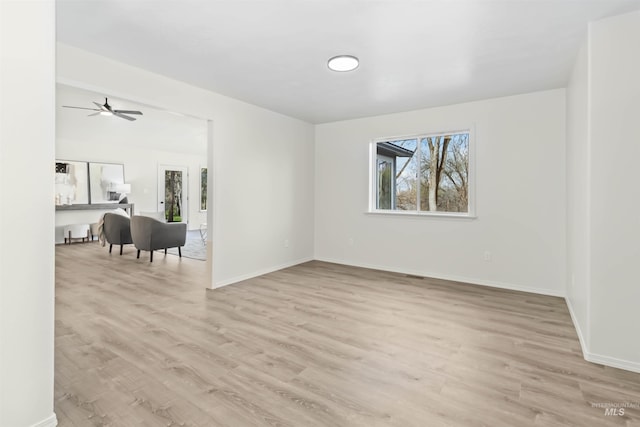 unfurnished room featuring baseboards, light wood-type flooring, and a ceiling fan