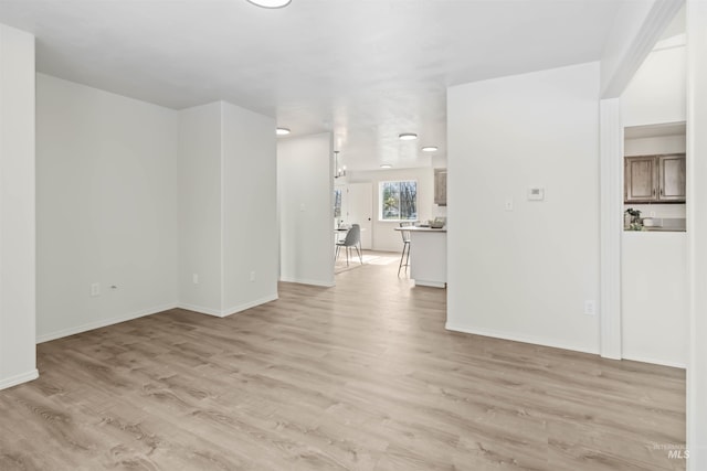 unfurnished living room featuring light wood finished floors and baseboards
