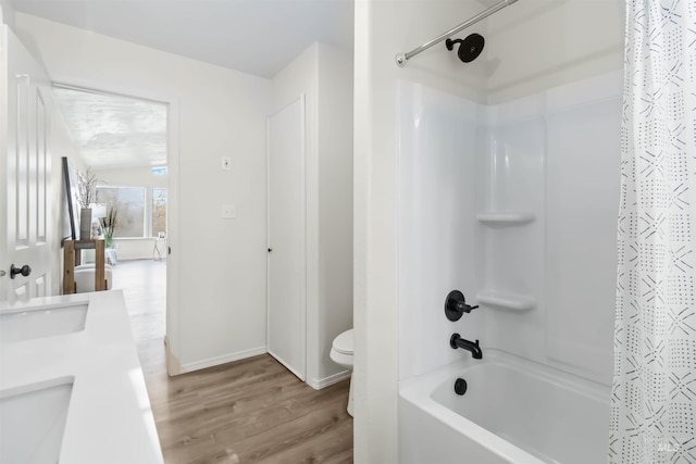 bathroom featuring a sink, toilet, shower / bath combo with shower curtain, double vanity, and wood finished floors