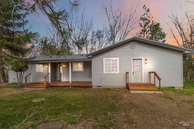back of property at dusk featuring crawl space, a yard, and a porch