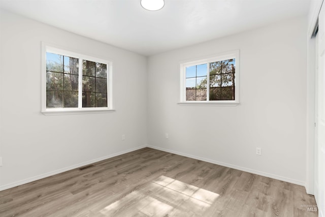 unfurnished room featuring light wood-type flooring, baseboards, and visible vents
