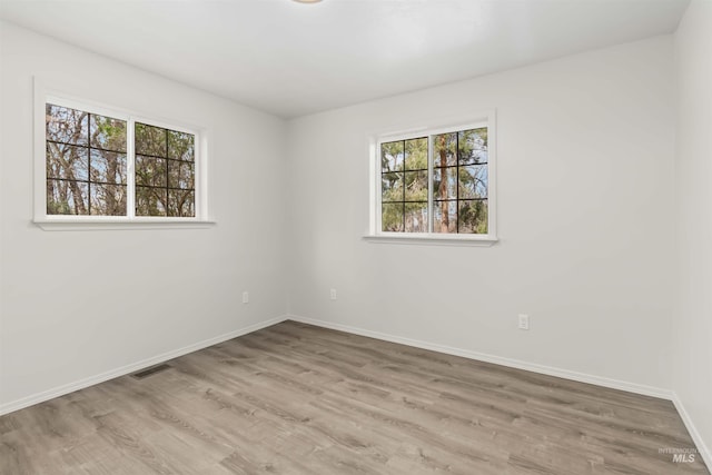 unfurnished room featuring visible vents, baseboards, and wood finished floors