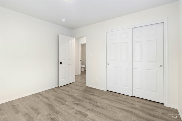 unfurnished bedroom with a closet, baseboards, and wood finished floors