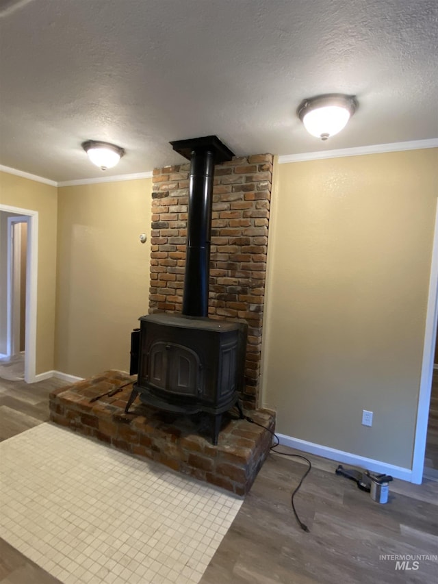 detailed view of wood finished floors, a textured ceiling, baseboards, a wood stove, and ornamental molding