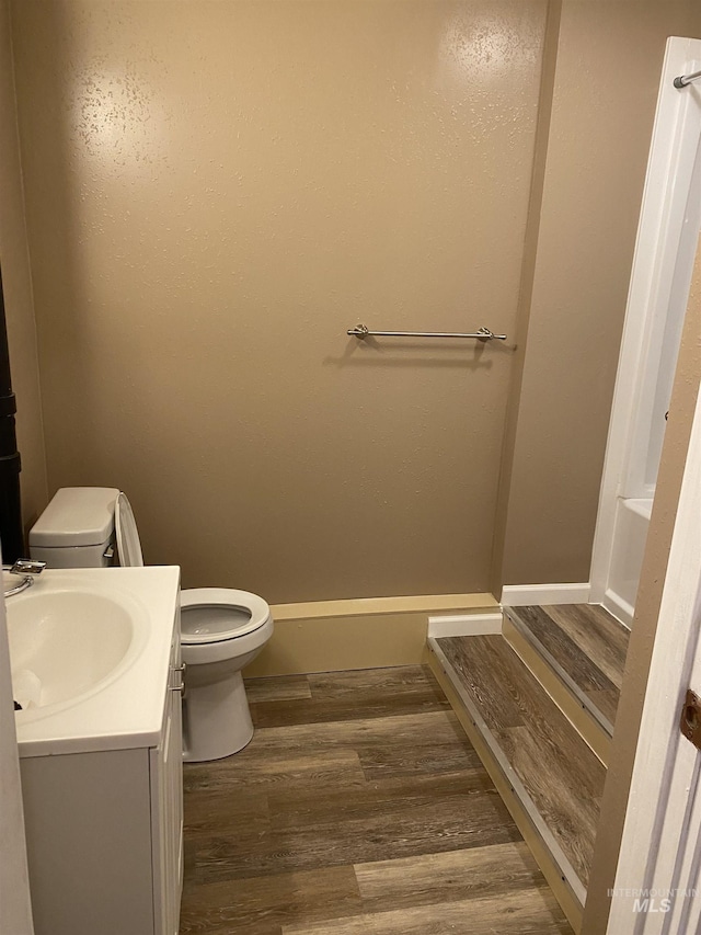 bathroom with toilet, wood finished floors, vanity, and baseboards