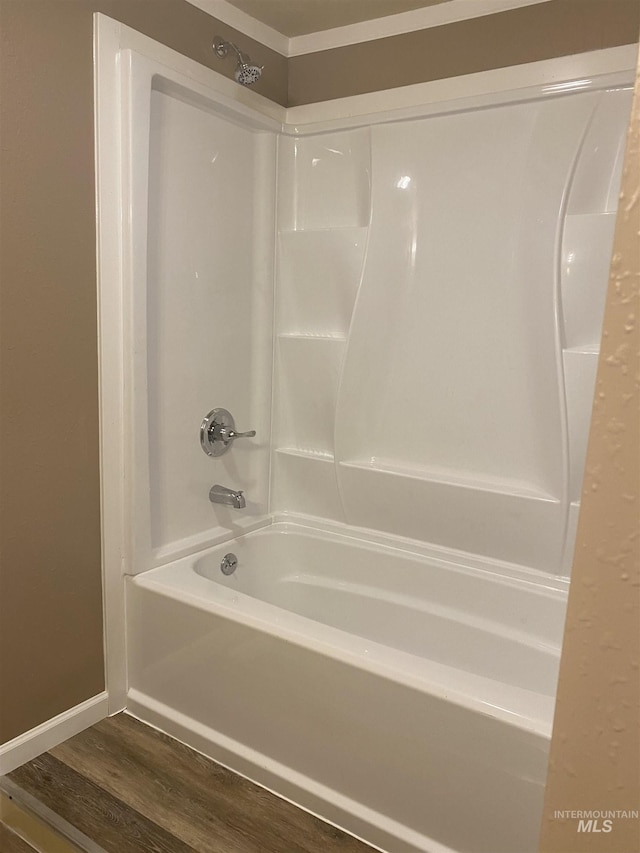 full bathroom with wood finished floors,  shower combination, and baseboards