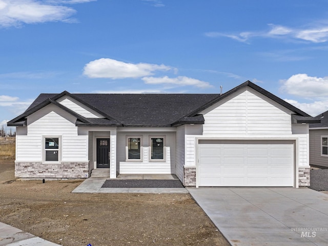 view of front of home with a garage, stone siding, concrete driveway, and roof with shingles