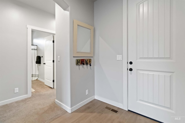 foyer entrance featuring wood finished floors, baseboards, and visible vents