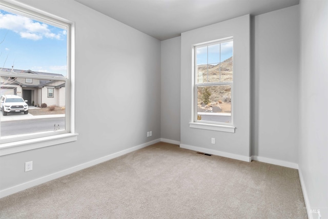 unfurnished room featuring carpet, visible vents, and baseboards