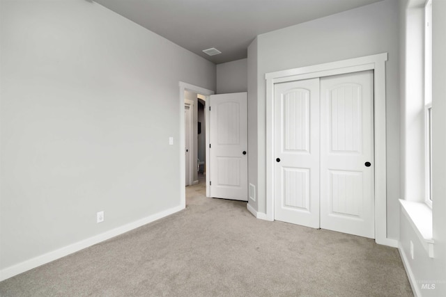 unfurnished bedroom featuring a closet, visible vents, baseboards, and carpet