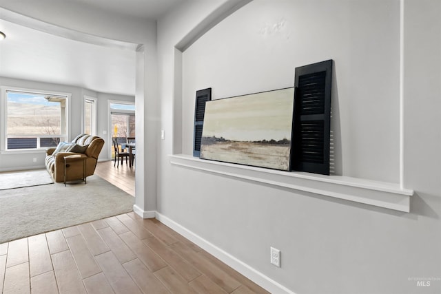 corridor with carpet floors, baseboards, and wood tiled floor