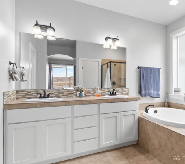 bathroom with decorative backsplash, a stall shower, and a sink