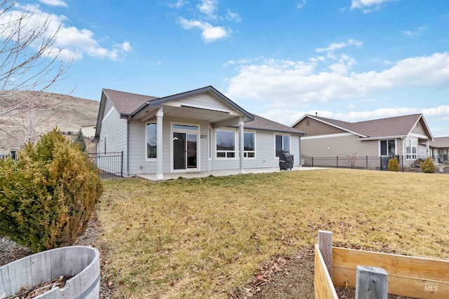 rear view of property featuring a yard and a fenced backyard