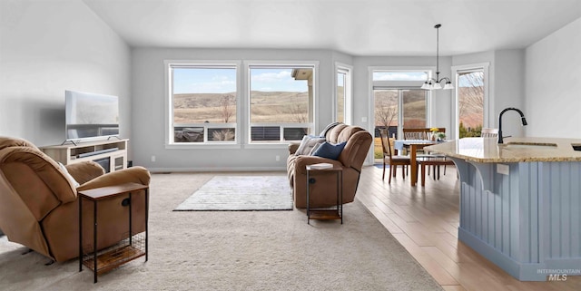 living area featuring baseboards, a notable chandelier, and light wood-style flooring