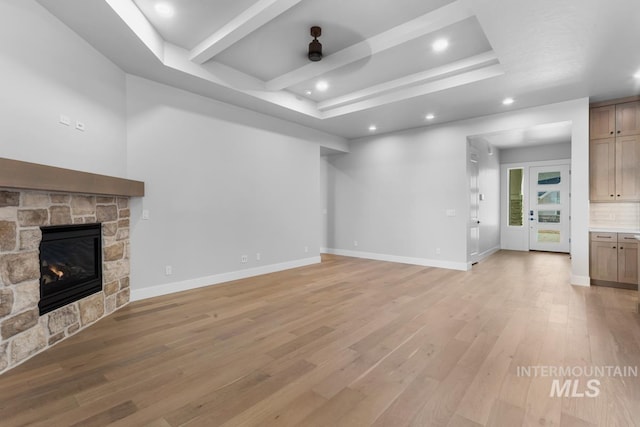 unfurnished living room with a stone fireplace and light hardwood / wood-style floors