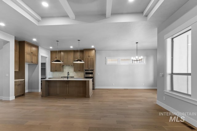 kitchen featuring hanging light fixtures, plenty of natural light, an island with sink, and a chandelier