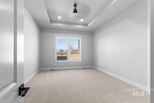 spare room featuring light carpet and a tray ceiling