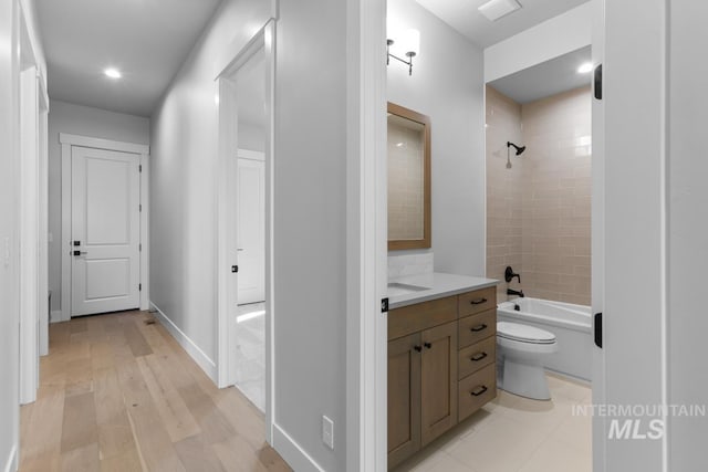 full bathroom with tiled shower / bath combo, vanity, hardwood / wood-style flooring, and toilet