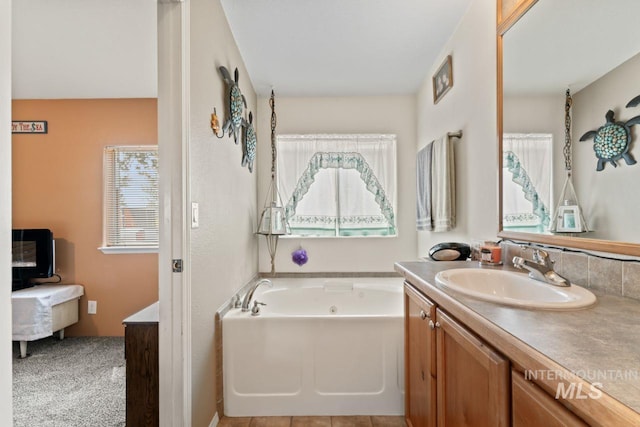 bathroom featuring connected bathroom, a whirlpool tub, and vanity