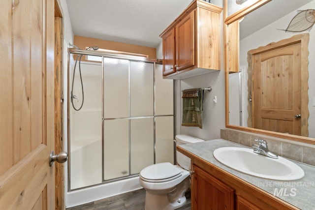 full bath featuring vanity, a shower stall, toilet, and wood finished floors