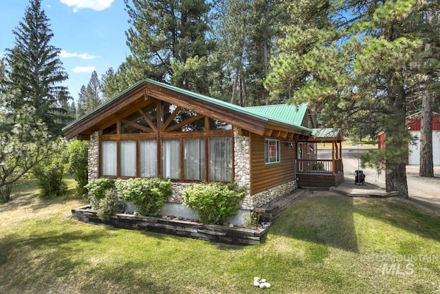 view of side of home with a lawn, metal roof, log veneer siding, and stone siding