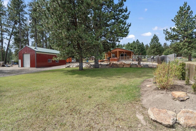 view of yard with fence, an outbuilding, a pole building, and driveway