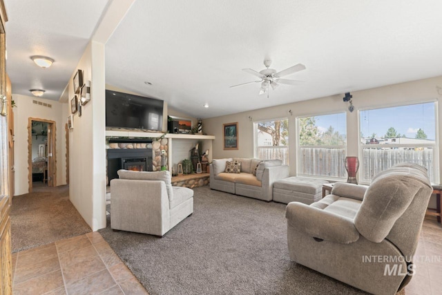 living area with carpet, a ceiling fan, a stone fireplace, and visible vents