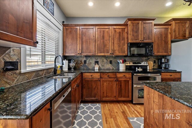 1063 Hitchcock St, Meridian, ID 83646 - kitchen with stainless steel appliances, a sink, light wood-style floors, dark stone counters, and decorative backsplash