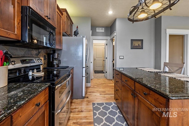 1063 Hitchcock St, Meridian, ID 83646 - kitchen with visible vents, black microwave, dark stone counters, double oven range, and light wood-style flooring
